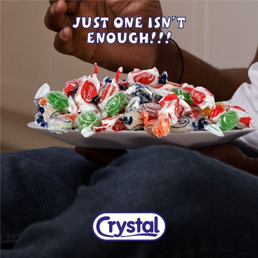 A hand holding a pile of Crystal sweets, with the words Just one isn't enough